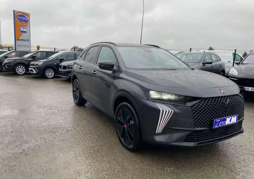 DS7 Crossback gris foncé en 3/4 avant droit sous la pluie, avec calandre large et feux LED distinctifs allumés.