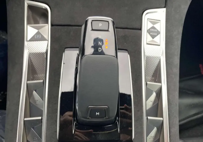 Vue rapprochée de la commande de boîte automatique noire du DS7 Crossback 2024 gris foncé avec boutons argentés autour.