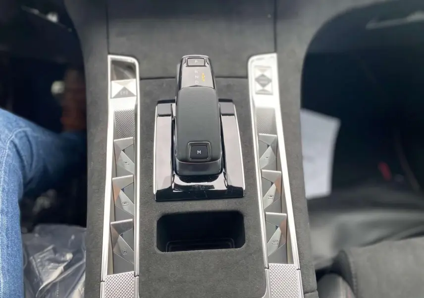 Gros plan sur la console centrale du DS7 Crossback 2024 gris foncé, mettant en valeur le levier de vitesse automatique et les boutons argentés.