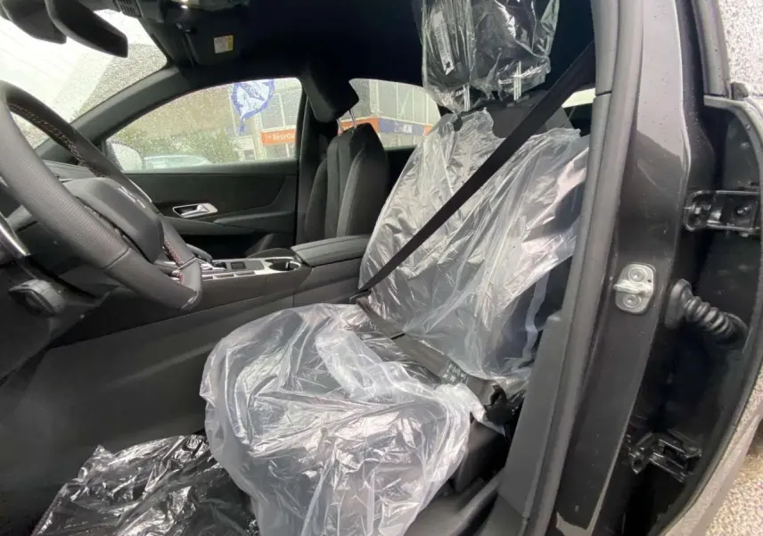 Vue intérieure côté conducteur du DS7 Crossback gris foncé 2024, siège avant protégé par une housse plastique.