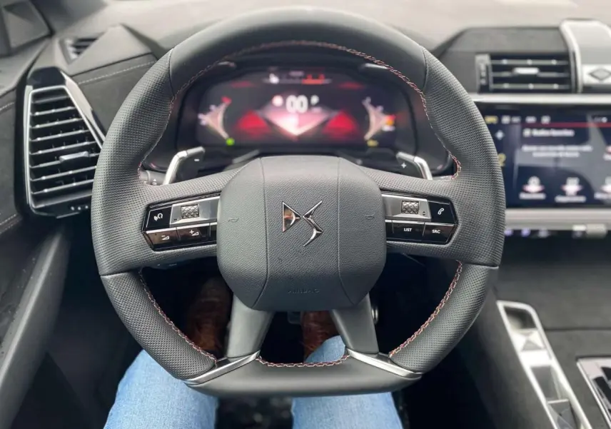 Vue rapprochée du volant au design carré du DS7 Crossback 2024 gris foncé, avec commandes intégrées et tableau de bord numérique.