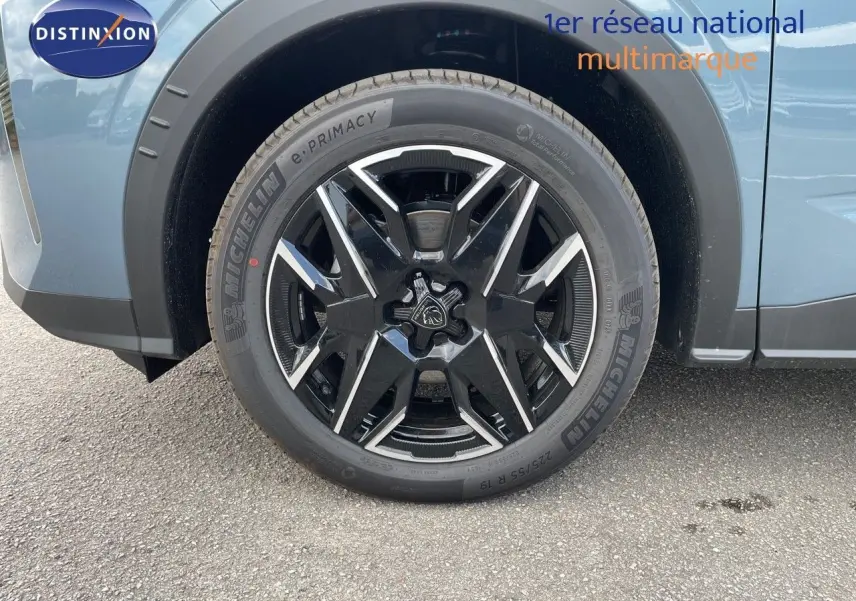 Gros plan sur la roue avant gauche du Peugeot 3008 Hybrid bleu Ingaro Metal avec jante noire et argentée.
