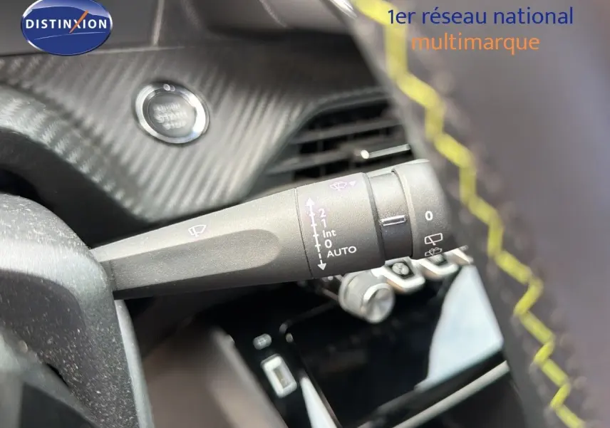 Gros plan sur la commande d'essuie-glace à gauche du volant avec surpiqûres jaunes dans l'habitacle d'une Peugeot 208 GT Line électrique.