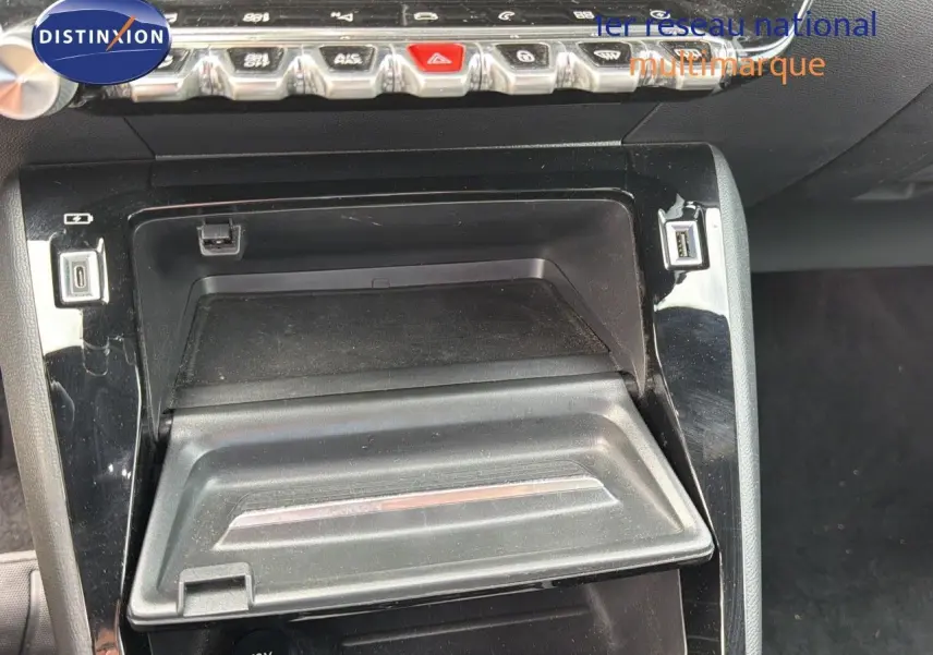 Gros plan sur la console centrale noire de la Peugeot 208 électrique 2020, avec rangement et prises USB visibles.