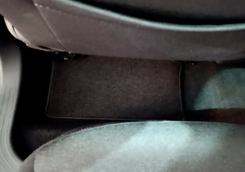 Vue rapprochée du sol côté passager arrière d’une Renault Clio Business E-TECH 140 gris foncé, tapis de sol visible.