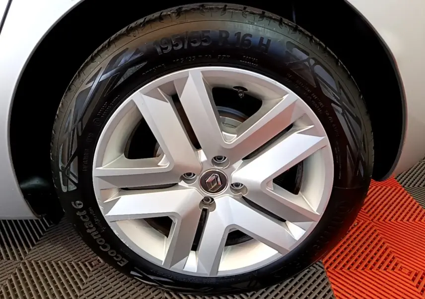 Gros plan sur la roue avant droite d’une Renault Clio gris foncé, mettant en valeur la jante alliage au design moderne.