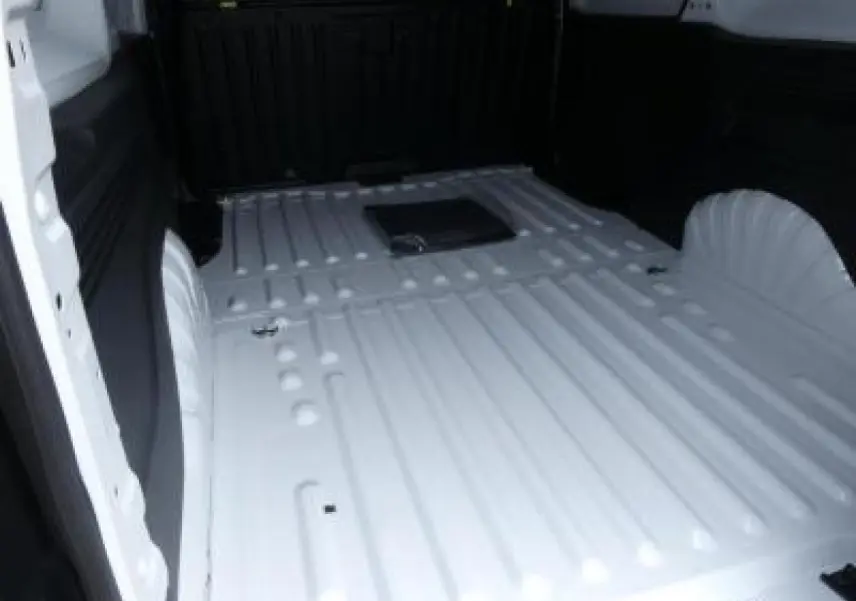 Vue intérieure du compartiment de chargement blanc du Peugeot Partner XL 950KG avec plancher métallique nervuré.