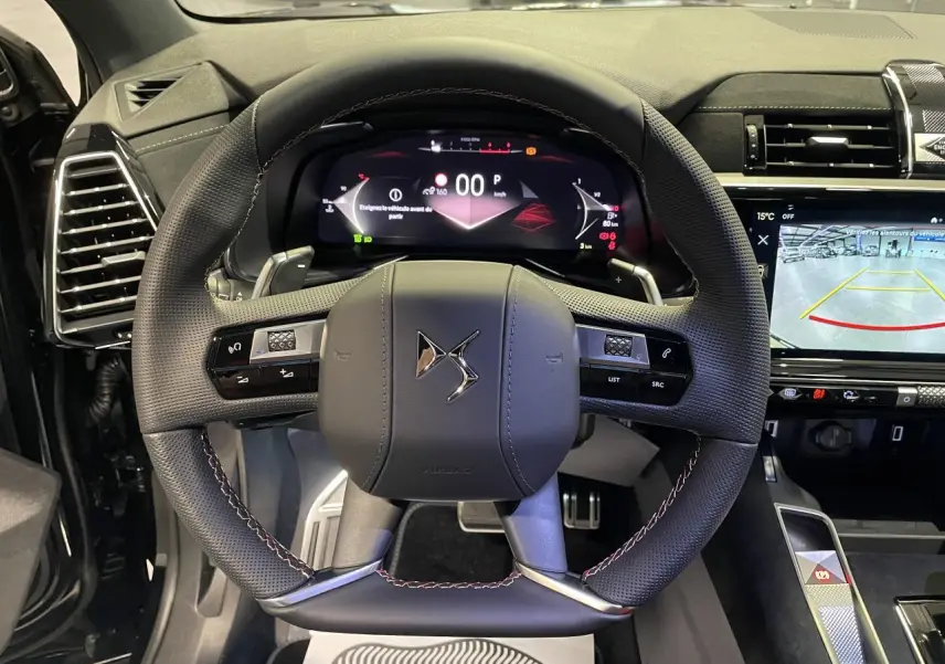 Vue intérieure centrée sur le volant DS en cuir perforé avec coutures rouges et tableau de bord numérique du DS7 Crossback noir.