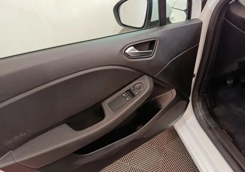 Vue intérieure côté conducteur de la porte noire d'une Renault Clio Business blanche avec commandes de vitres et rétroviseur.