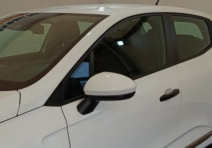 Vue latérale côté gauche d'une Renault Clio Business blanche 2021, mettant en valeur la poignée de porte et le rétroviseur extérieur.