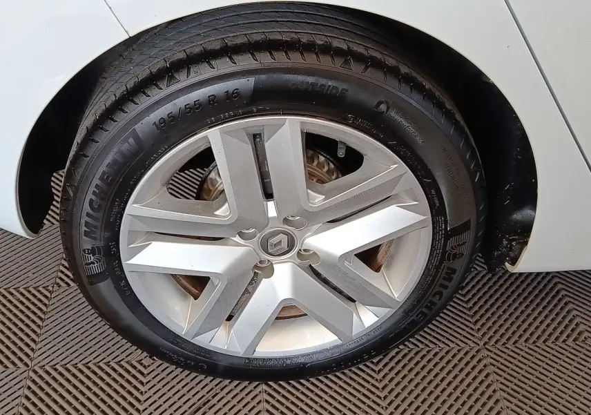 Gros plan sur la roue avant droite d'une Renault Clio blanche, avec jante alliage et pneu Michelin visible.