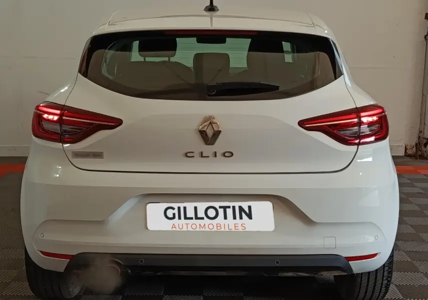Vue arrière d'une Renault Clio Business blanche de 2021 avec feux LED allumés dans un garage.