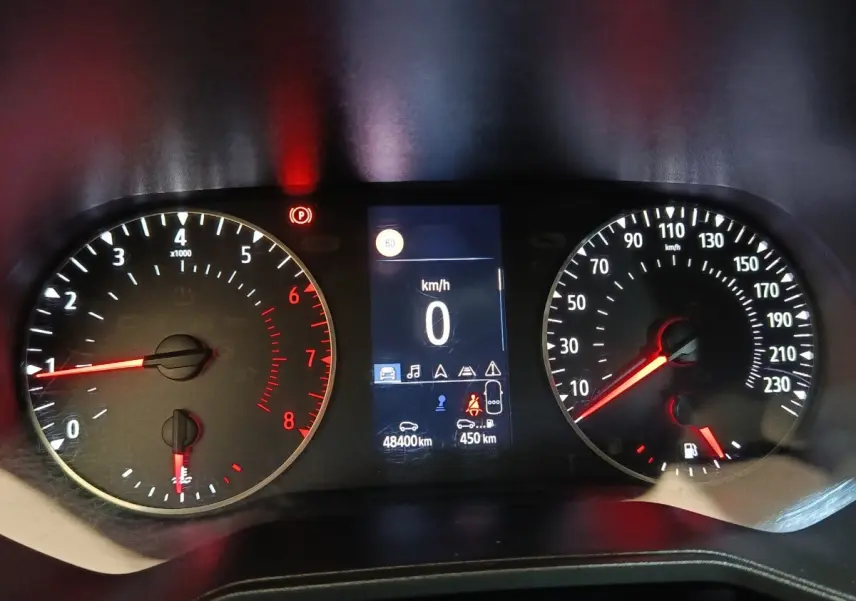 Tableau de bord de Renault Clio Business blanc 2021, affichage numérique central et compteurs analogiques éclairés rouge.