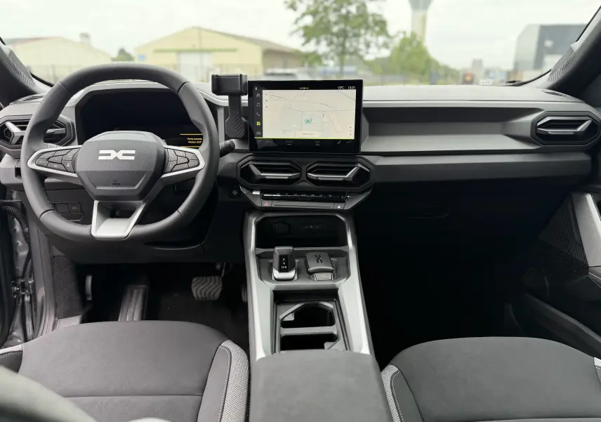 Vue intérieure avant du tableau de bord du Dacia Bigster gris schiste avec écran tactile central et volant multifonction.