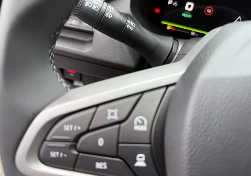Gros plan sur les commandes au volant du Dacia Bigster 2026, avec tableau de bord numérique en arrière-plan.