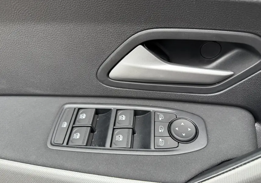 Gros plan sur la commande des vitres et le bouton de réglage des rétroviseurs côté conducteur d’un Dacia Bigster gris schiste.