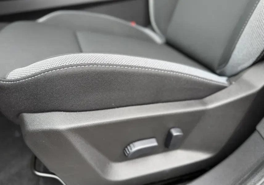 Détail du réglage électrique du siège avant en tissu gris du Dacia Bigster 2026, version hybride.