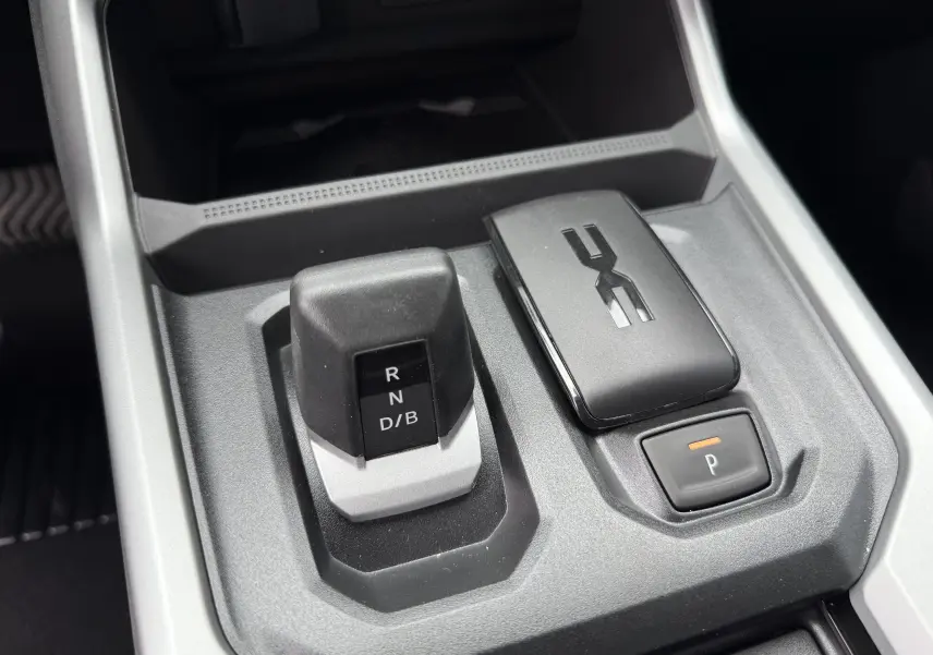 Gros plan sur la console centrale grise schiste du Dacia Bigster 2026, avec levier de vitesses automatique et bouton de parking.