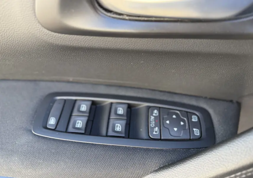 Gros plan sur les commandes des vitres électriques côté gauche du Renault Kadjar 2019, finition tissu noire.