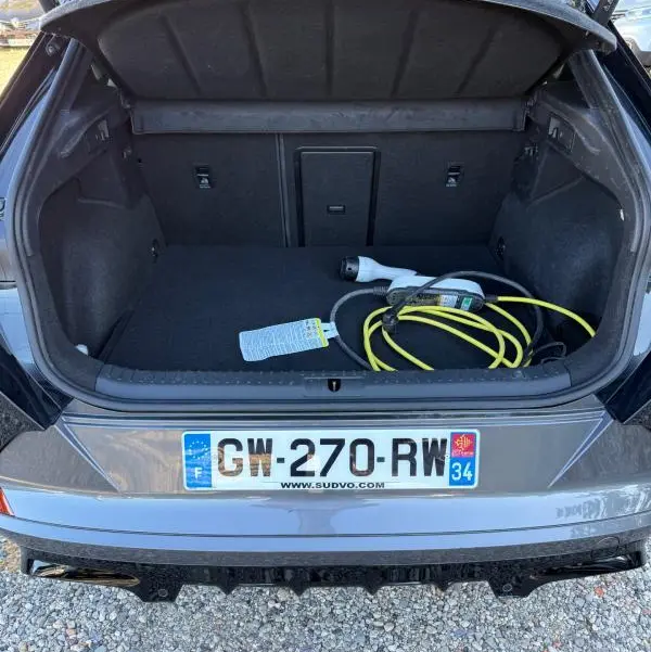Coffre ouvert vu de l'arrière d'une CUPRA Formentor noir 2024 avec câble de recharge hybride visible.