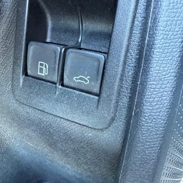 Gros plan sur les boutons d’ouverture de trappe à carburant et coffre dans l’habitacle noir du CUPRA Formentor 2024.