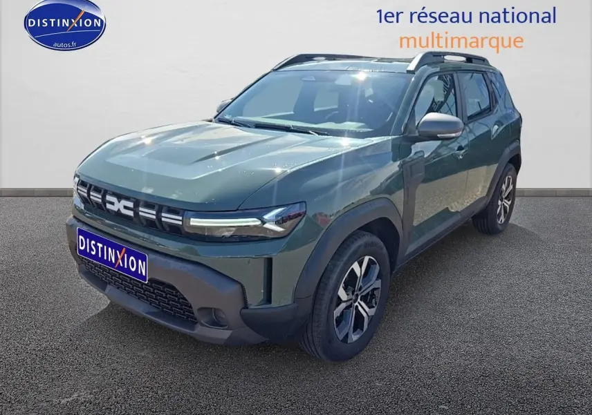 Dacia Duster vert kaki en 3/4 avant droit avec barres de toit et jantes alu visibles sur fond neutre.
