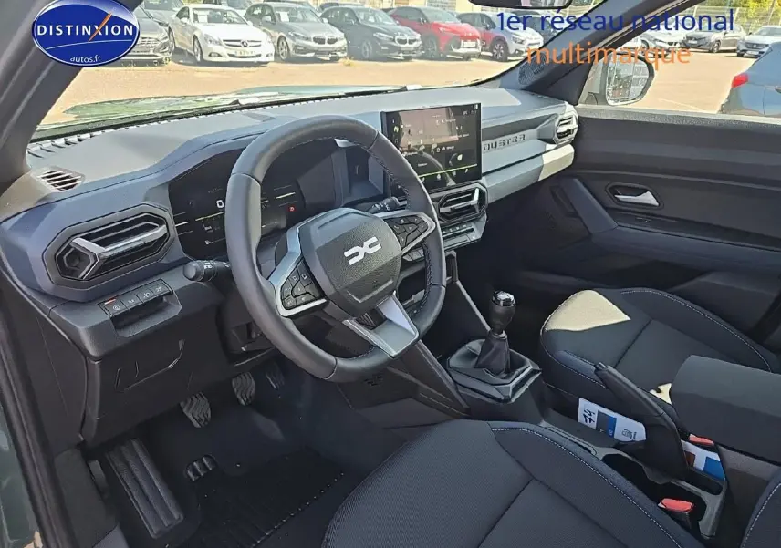 Intérieur avant du Dacia Duster 2025 vert kaki, volant multifonction, boîte manuelle et écran tactile central visible.