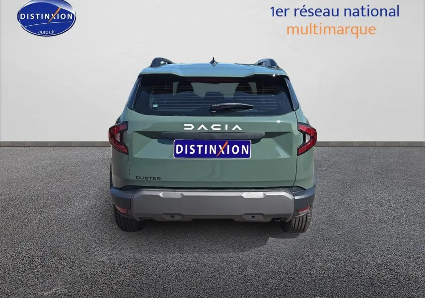 Vue arrière d'un Dacia Duster vert kaki 2025 avec barres de toit et bouclier arrière gris.