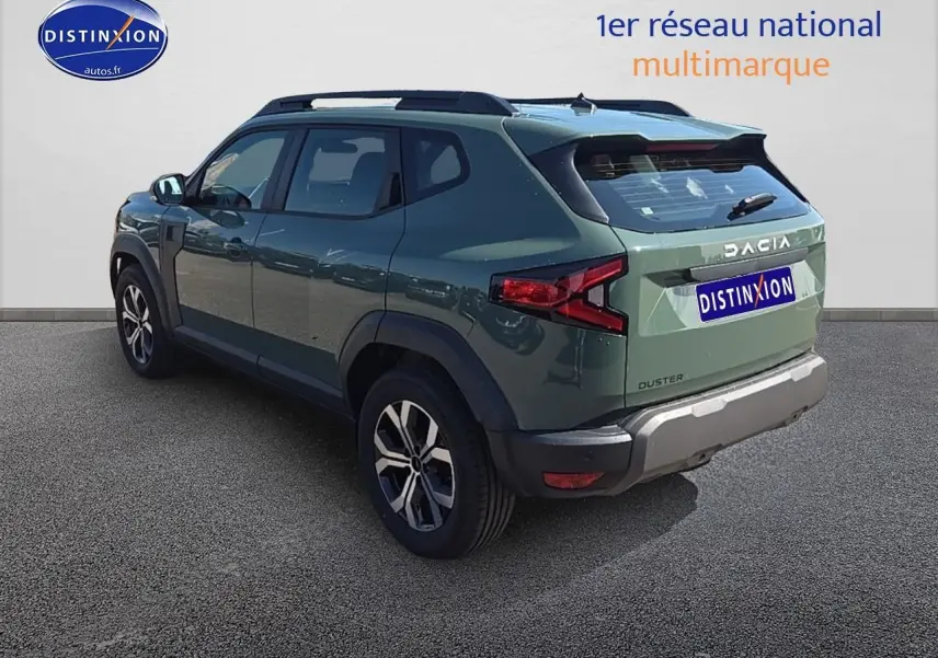 Vue 3/4 arrière droite du Dacia Duster vert kaki 2025 avec barres de toit et jantes alu distinctives.