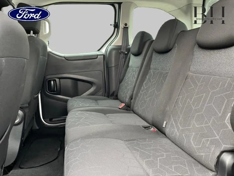 Vue latérale intérieure sur la banquette arrière grise du Peugeot Partner Tepee blanc avec porte coulissante ouverte