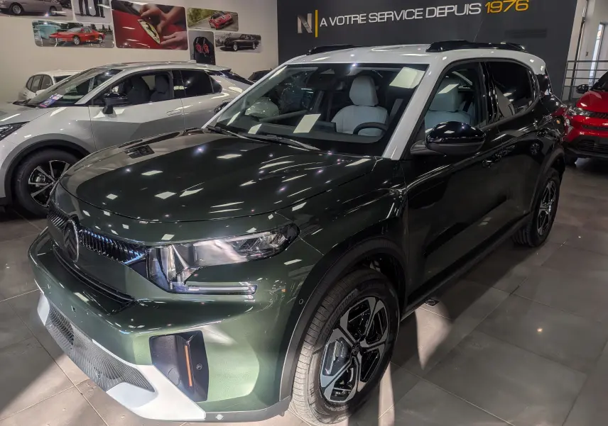 Citroën C3 Aircross hybride Vert Montana avec toit blanc, vue 3/4 avant droit en showroom lumineux.