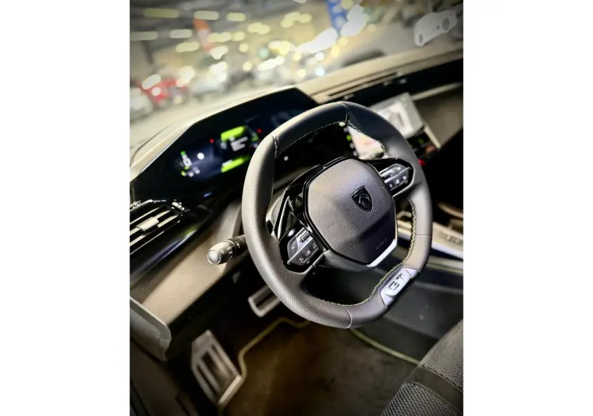Vue intérieure rapprochée du volant cuir GT et du combiné numérique de la Peugeot 308 gris selenium 2025.