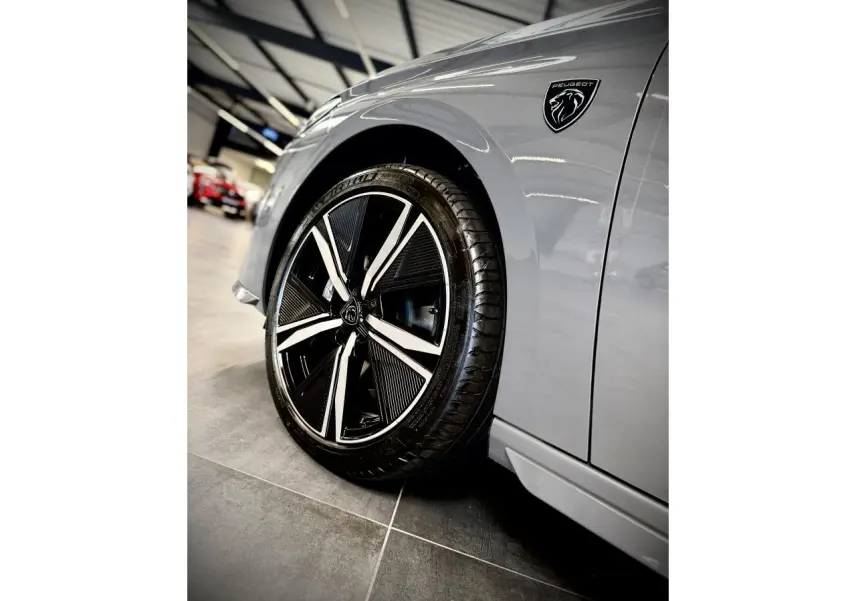 Gros plan sur la roue avant gauche et l’aile gris sélénium d’une Peugeot 308 avec logo noir brillant Lion.