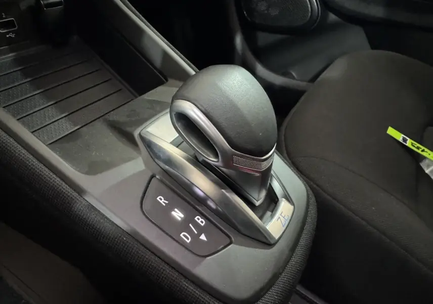Gros plan sur le levier de vitesses automatique noir avec logo ZE dans l’habitacle de la Renault ZOE blanche.