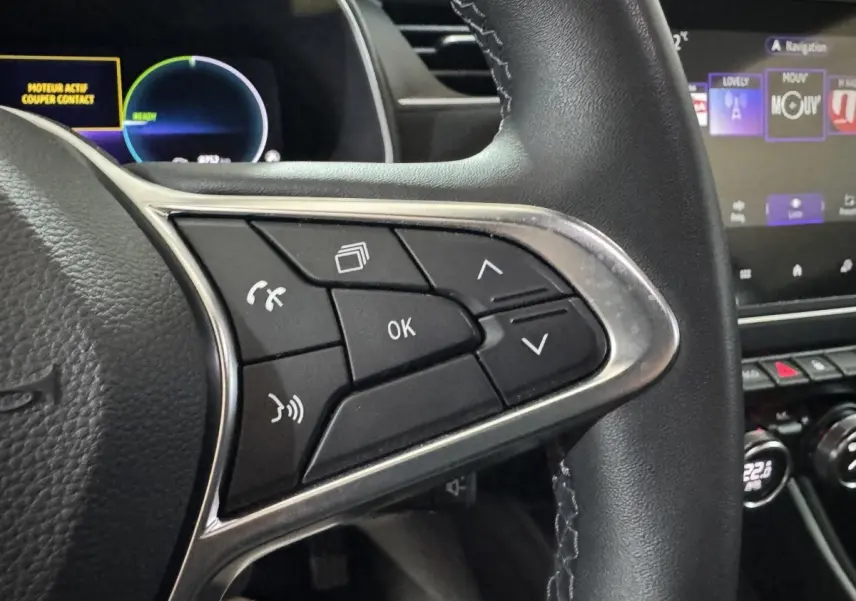 Gros plan sur les commandes au volant à droite en cuir noir de la Renault ZOE Business Rev R110 2020, avec écran tactile en arrière-plan.