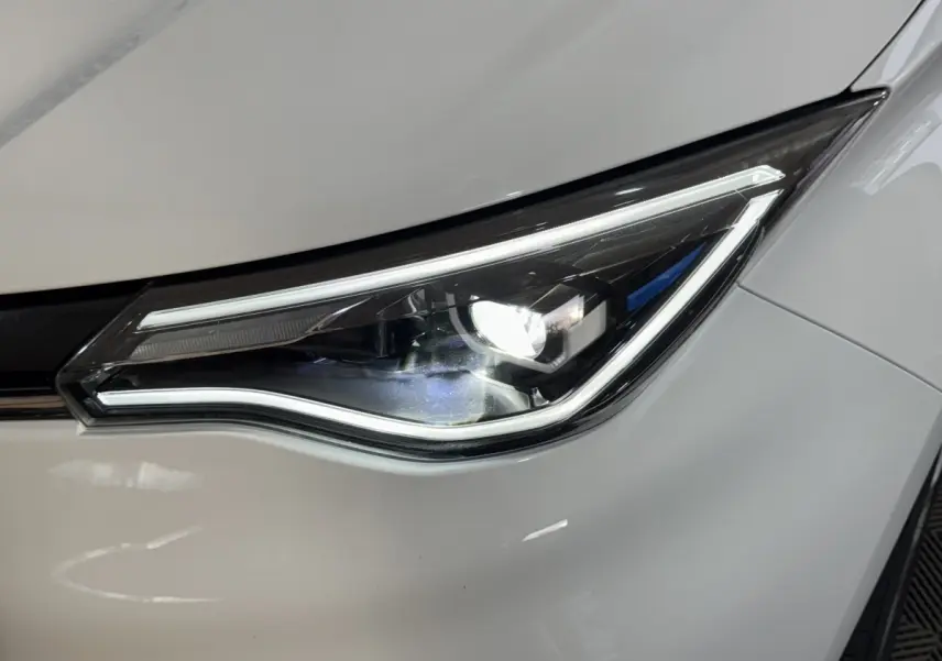 Gros plan sur le phare avant droit allumé d'une Renault ZOE Business Rev R110 blanche de 2020.