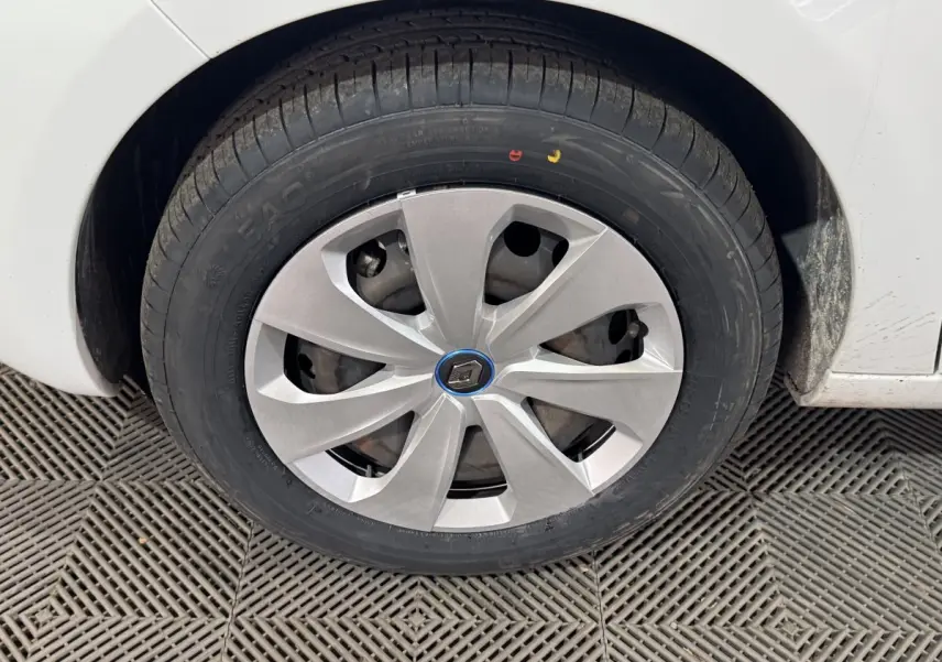 Gros plan sur la roue avant droite d'une Renault ZOE blanche avec enjoliveur argenté et logo Renault au centre.