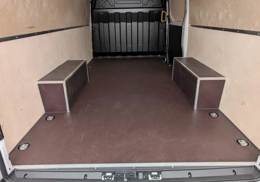 Vue intérieure arrière du fourgon Iveco Daily blanc, plancher antidérapant marron avec habillages latéraux en bois clair.