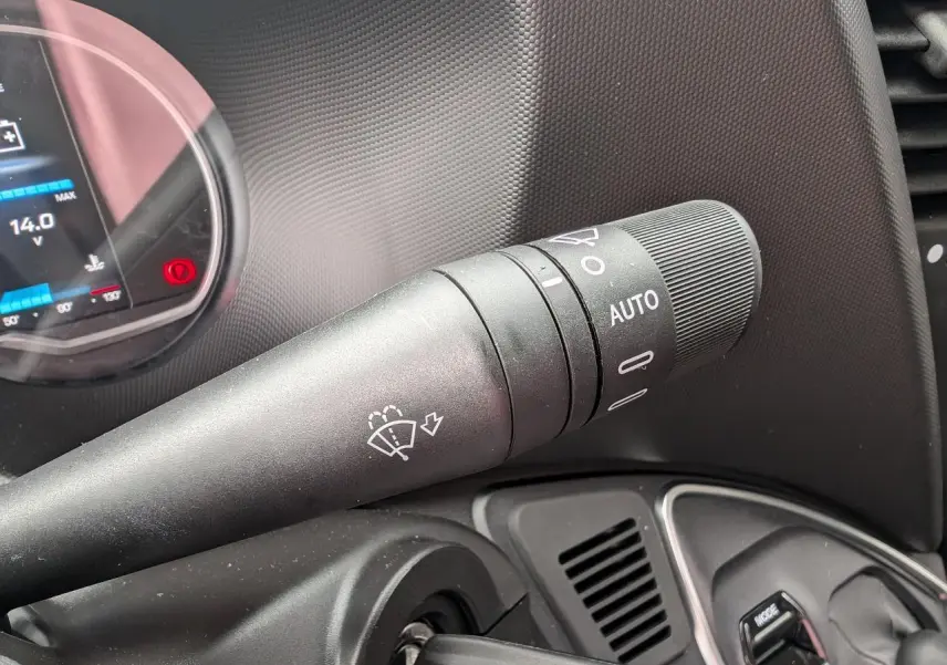 Gros plan sur la commande d’essuie-glace à gauche du tableau de bord noir du Iveco Daily blanc 2025.