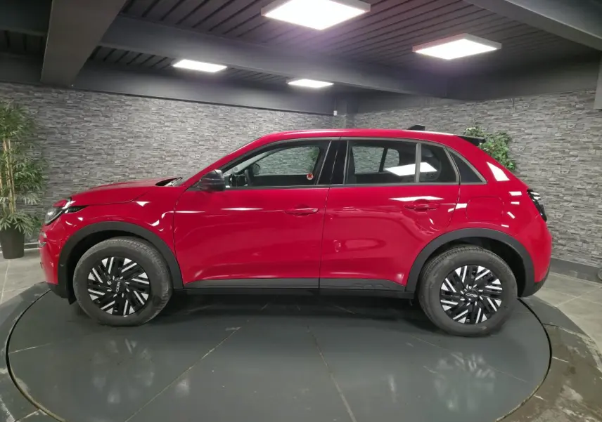 Vue de profil côté gauche d'une FIAT 600 rouge 2024 avec jantes acier bicolores et coques de rétroviseurs noires.