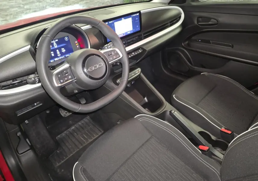 Vue intérieure avant droite du Fiat 600 1.2 Hybrid 2024 avec tableau de bord noir mat et volant Soft-Touch.