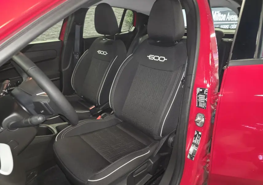 Vue intérieure côté conducteur du FIAT 600 rouge 2024, sièges tissu noir avec logo 600 brodé blanc.