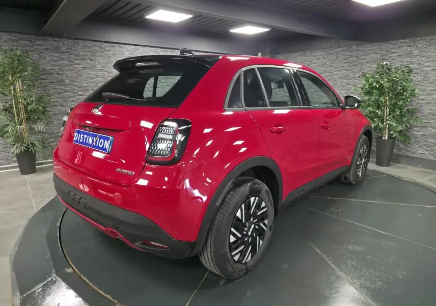 Vue 3/4 arrière droite d'une FIAT 600 rouge 2024 avec toit noir, feux arrière LED et jantes acier bicolores.