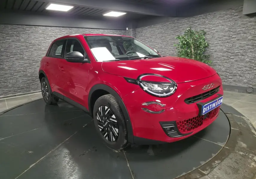 Vue 3/4 avant gauche d'une FIAT 600 rouge 2024 avec jantes acier bicolores et coques de rétroviseurs noires.