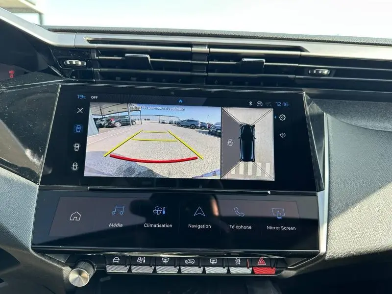 Vue intérieure du tableau de bord de la Peugeot 308 2025 avec écran tactile affichant la caméra de recul et l'aide au stationnement.