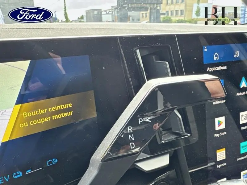 Gros plan sur la console centrale d’un Ford avec levier de vitesses et écran tactile affichant un message de sécurité.