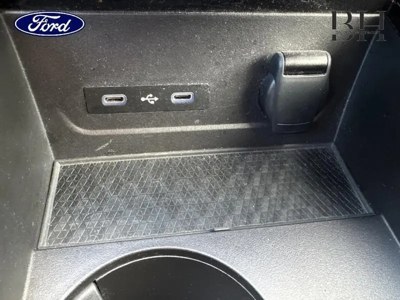 Détail intérieur montrant deux ports USB-C et une prise 12V dans le rangement central noir du Renault Espace rouge 2024.