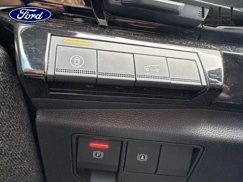 Boutons de commande du coffre et du frein de stationnement sur tableau de bord noir d'une Renault Espace rouge 2024.