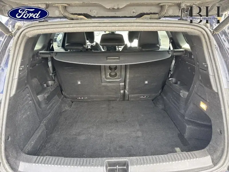 Coffre ouvert vu de l'arrière d'un Renault Espace 1.2 E-Tech rouge, avec cache-bagages et sièges arrière en tissu gris.