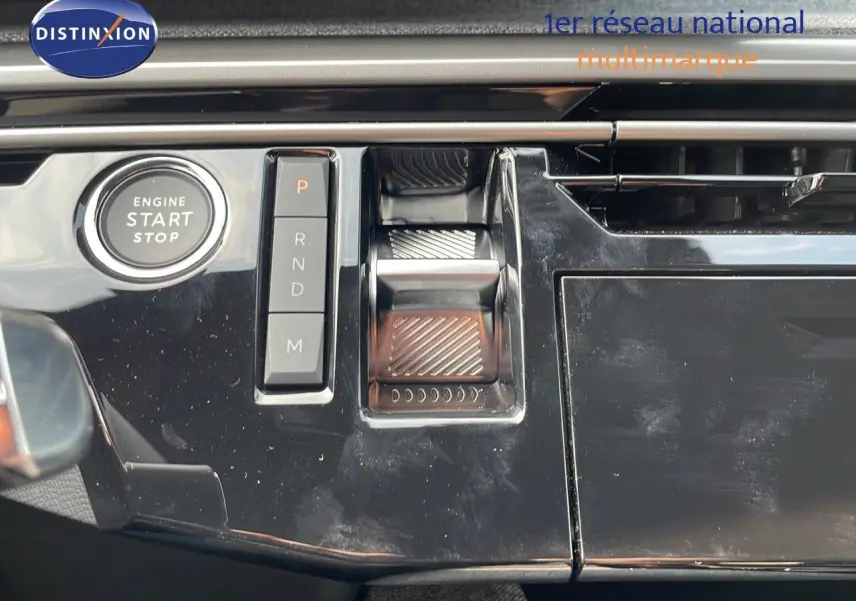 Gros plan sur la console centrale noire brillante du Peugeot 3008 Hybrid 2025 avec boutons de sélection de vitesse et démarrage moteur.